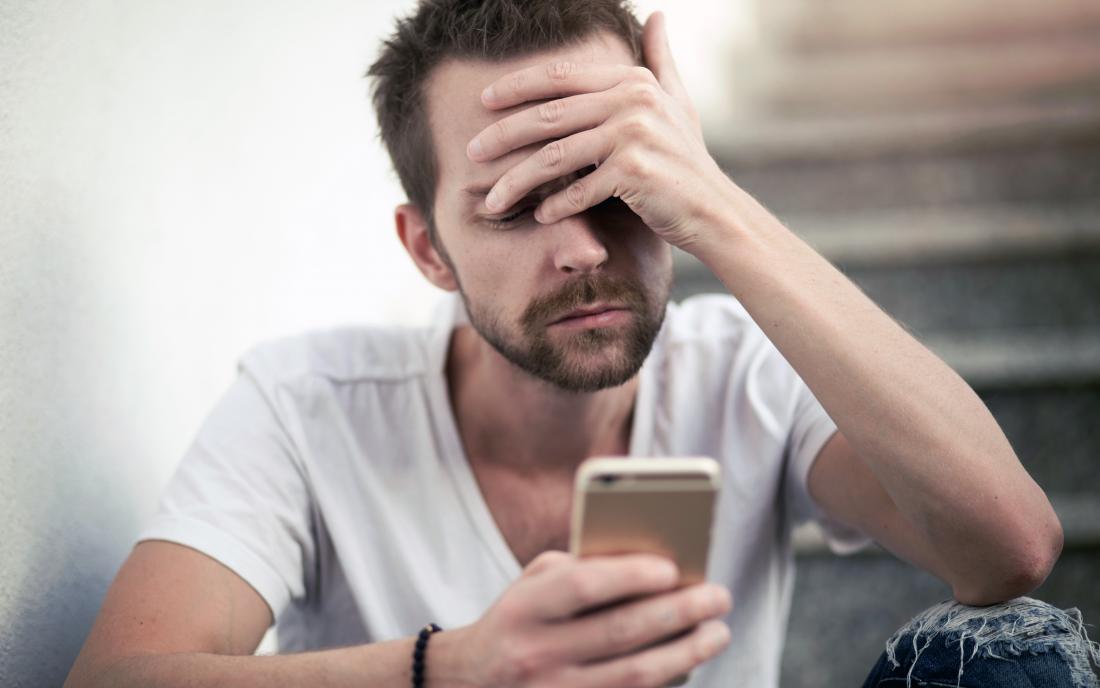 a man checking his messages on his phone from a partner because he has Obsessive love disorder disorder 