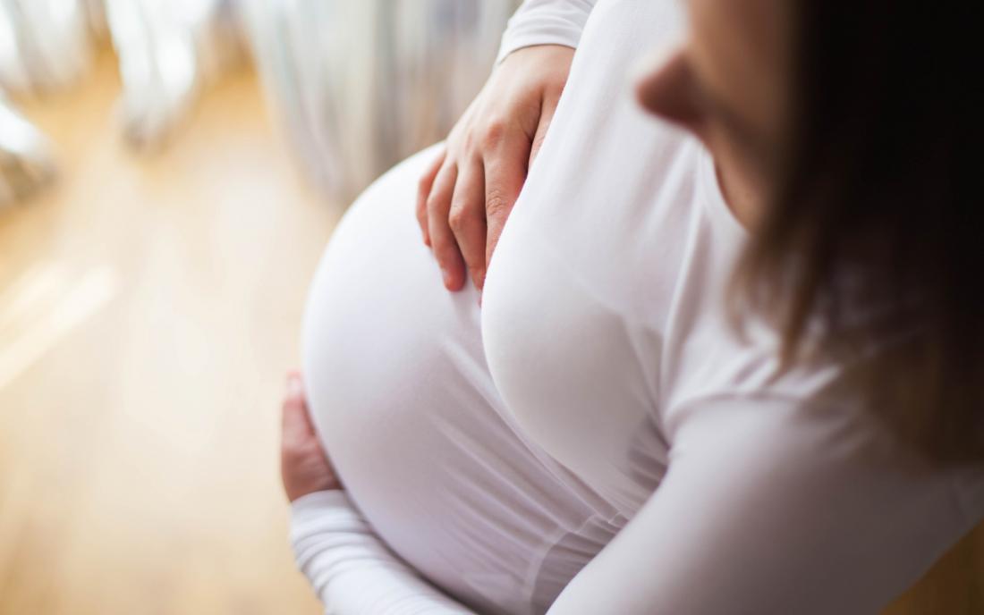 a pregnant woman holding her belly and wondering if the myths about pregnancy are correct 