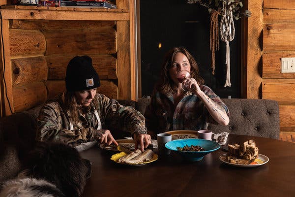 Iliana Regan cut into some walleye she smoked outside as she shared a Saturday family supper at the Milkweed Inn with her wife, Anna Hamlin, and Georgie, one of their three dogs.