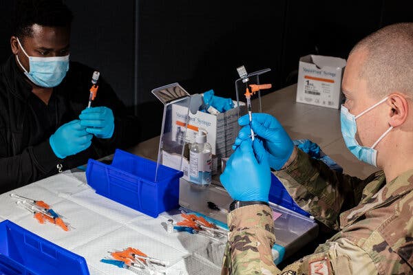 A member of the U.S. military and an employee of the New Jersey Institute of Technology prepared doses of the Pfizer-BioNTech vaccine at an immunization site in Newark last month.