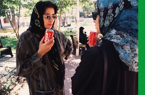 two women wearing colorful veils and sunglasses drink coca cola out of cans in a park in north tehran, iran, may 1995 photo by kaveh kazemigetty images