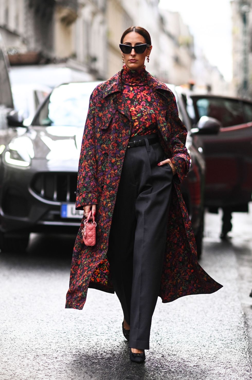 woman in a dark floral coat walking down a street