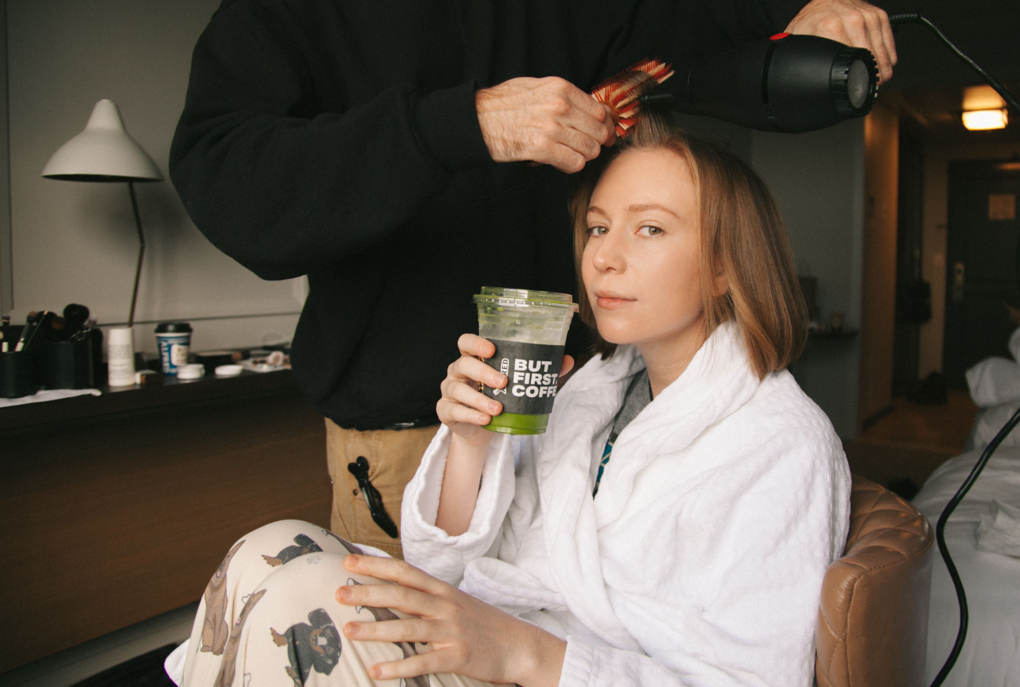 hannah einbinder holding a green juice as her hair is styled