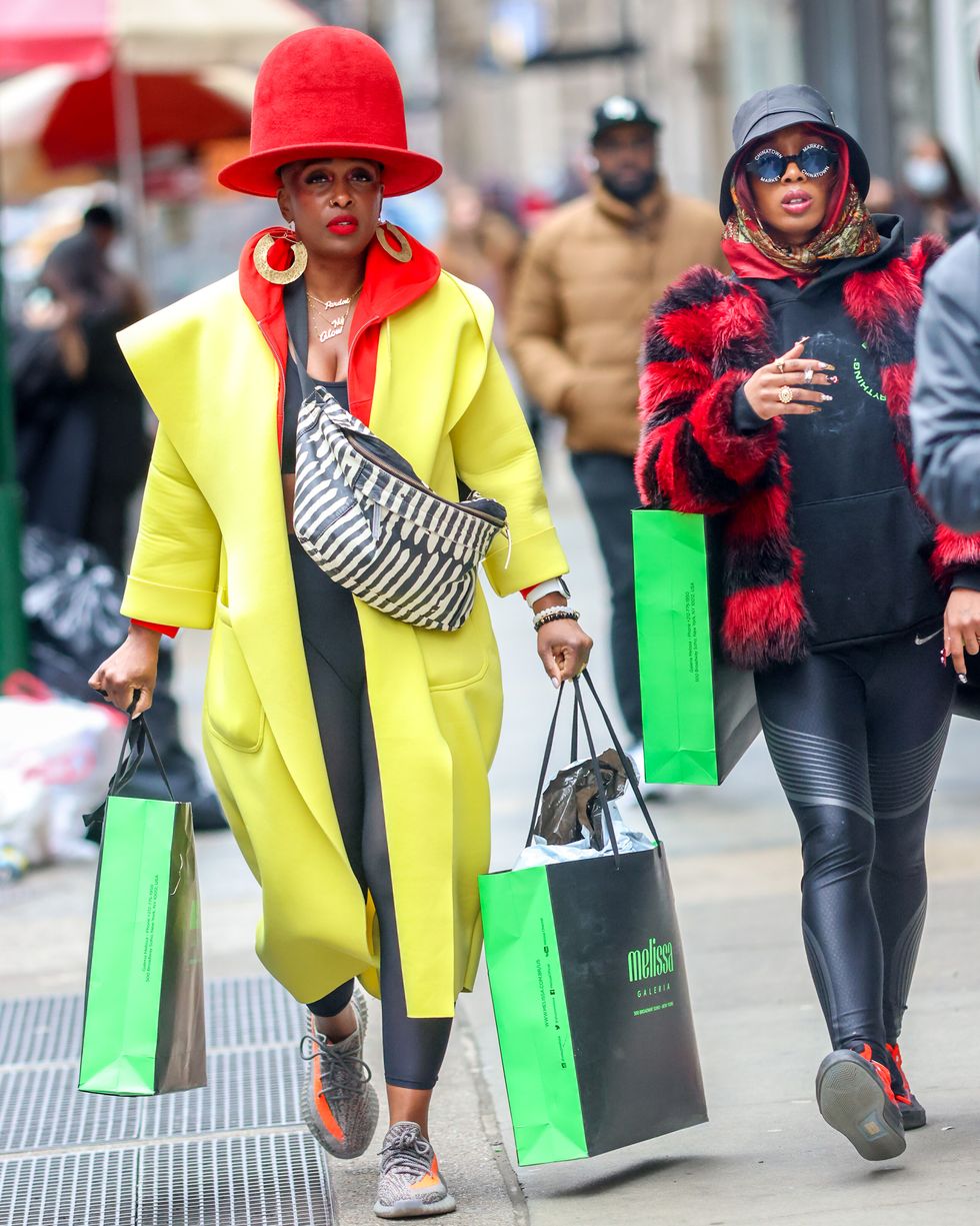 a couple of women walking down a sidewalk with shopping bags