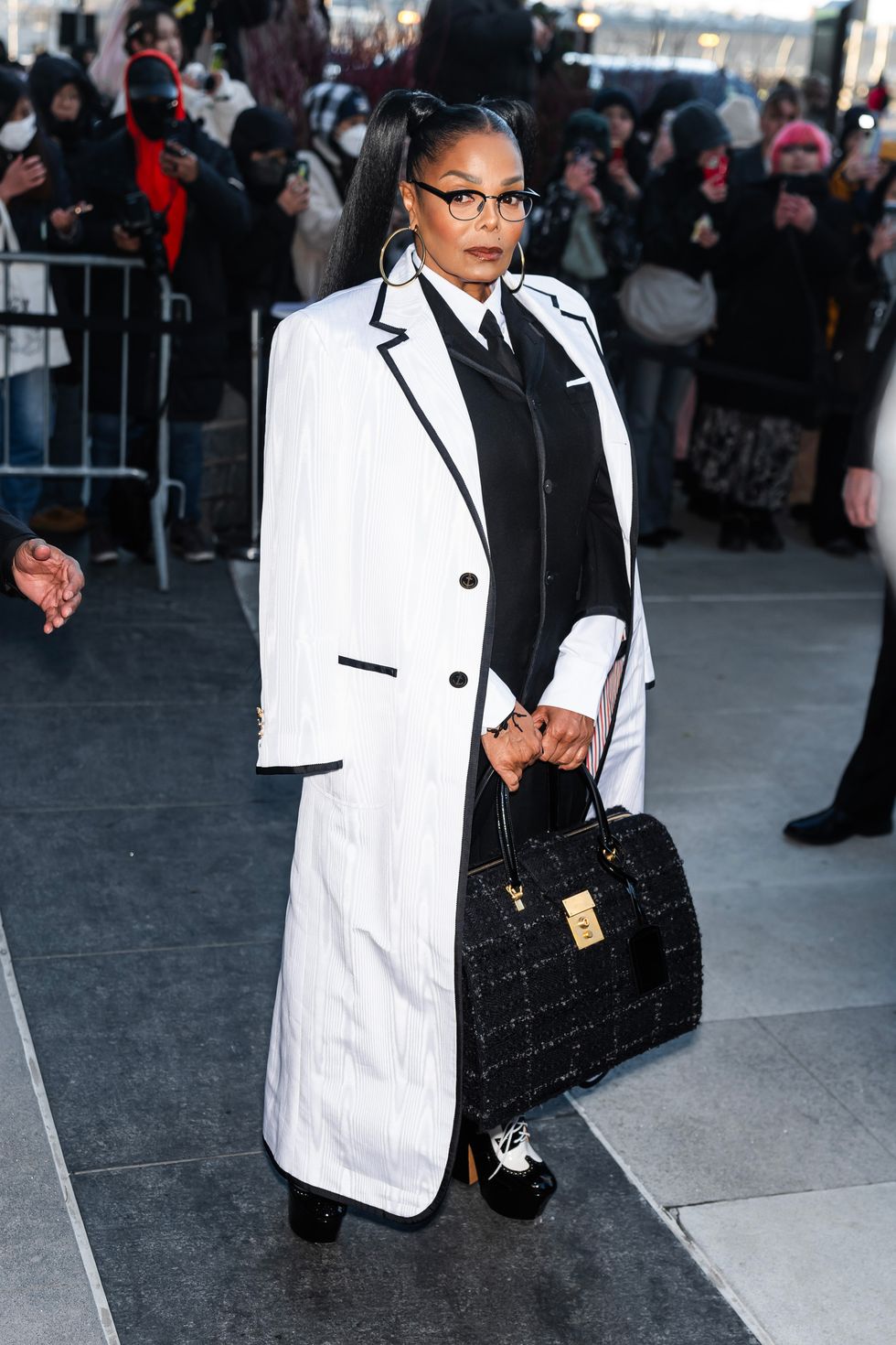 a black woman wearing a white oversized coat, glasses and a suit