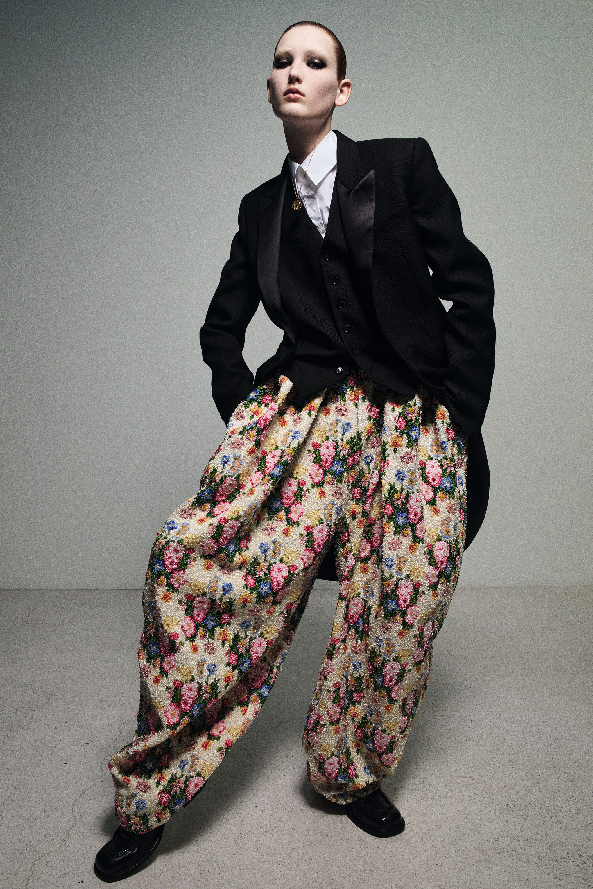 a woman wearing a suit jacket and oversized floral pants