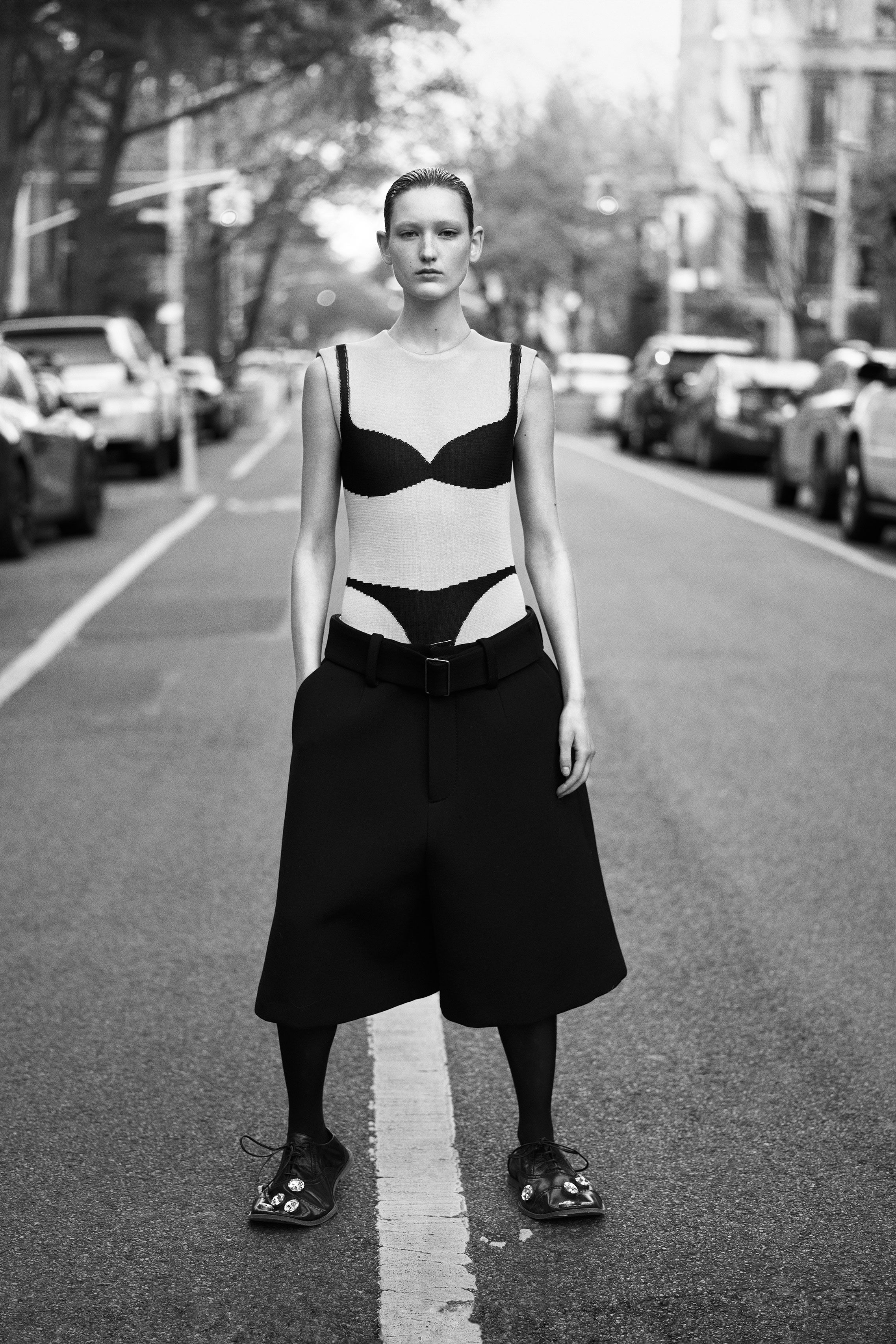 a woman standing in the middle of a street wearing shorts and a trompe l'oeil bra and underwear top