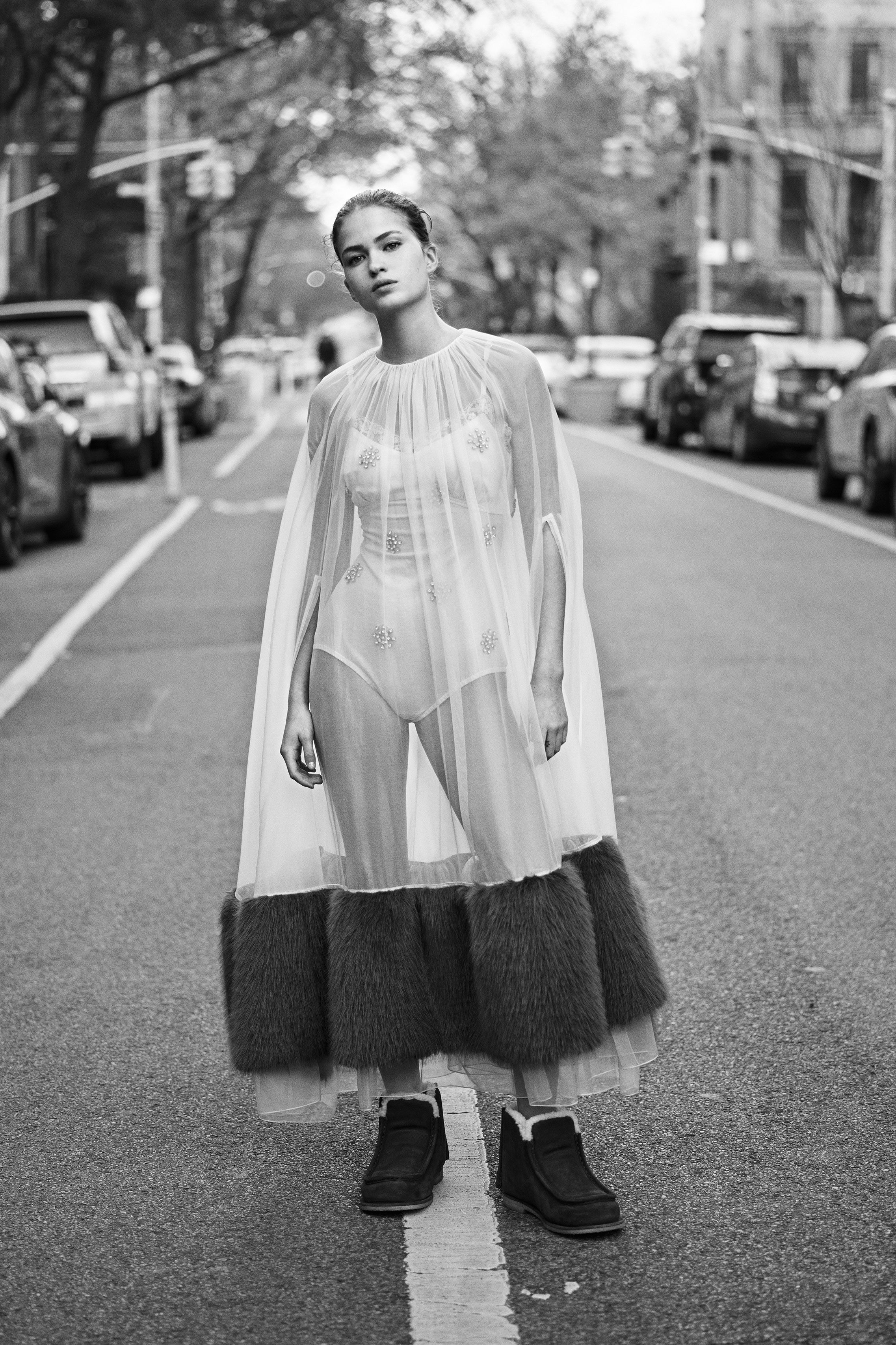 a woman in a transparent cape standing in the middle of a street