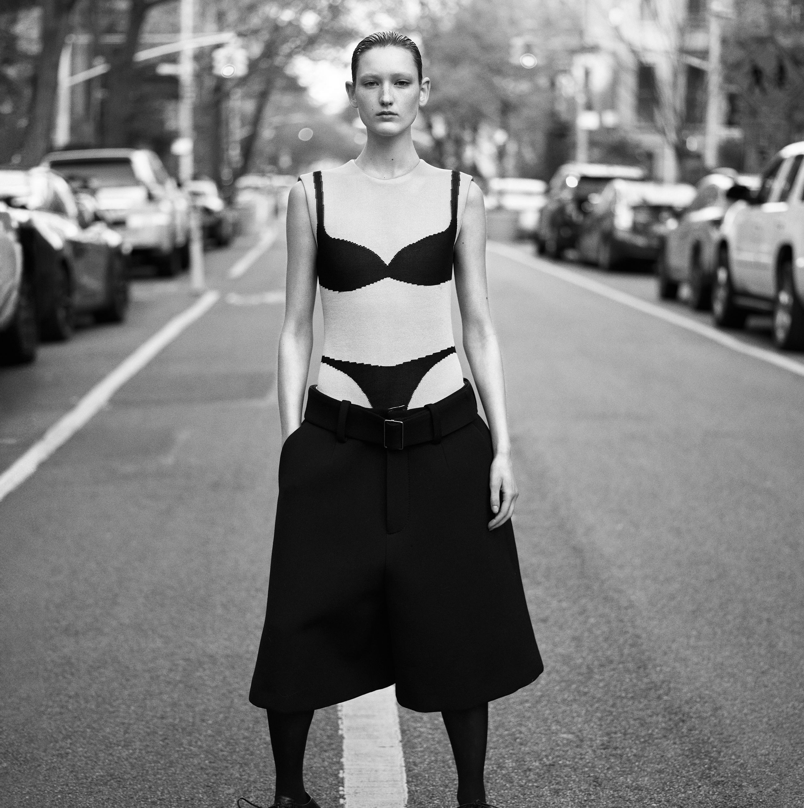 a woman standing in the middle of a street wearing shorts and a trompe l'oeil bra and underwear top