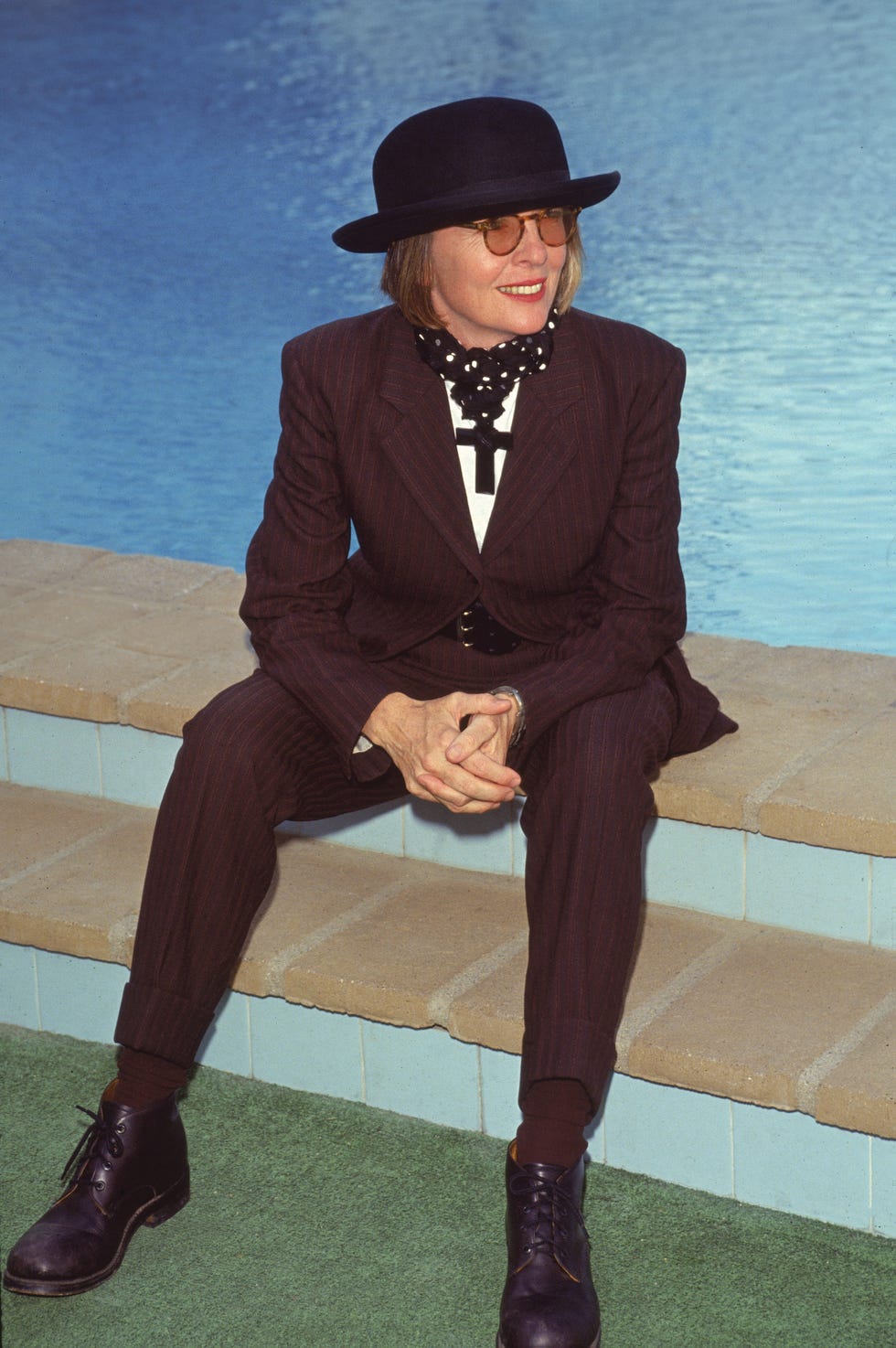 a woman in a hat and glasses sitting on steps