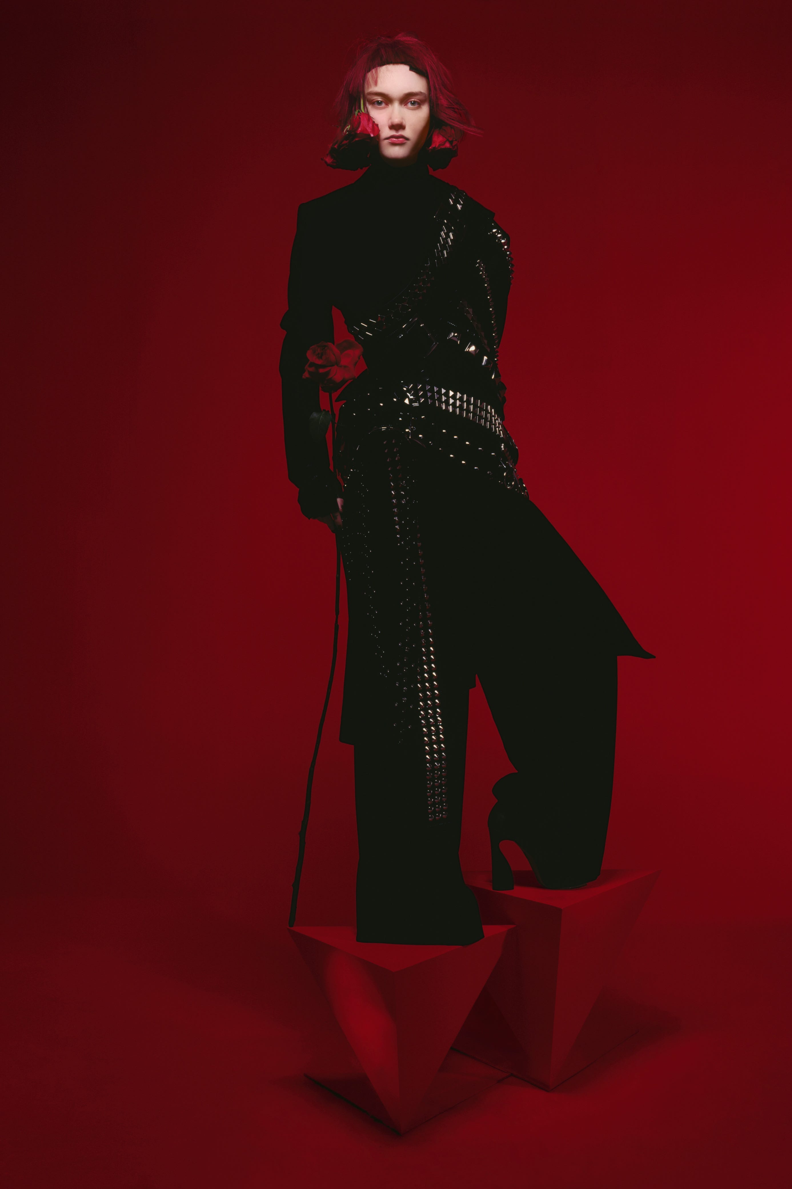 a woman in a black and silver outfit standing on two triangular red blocks