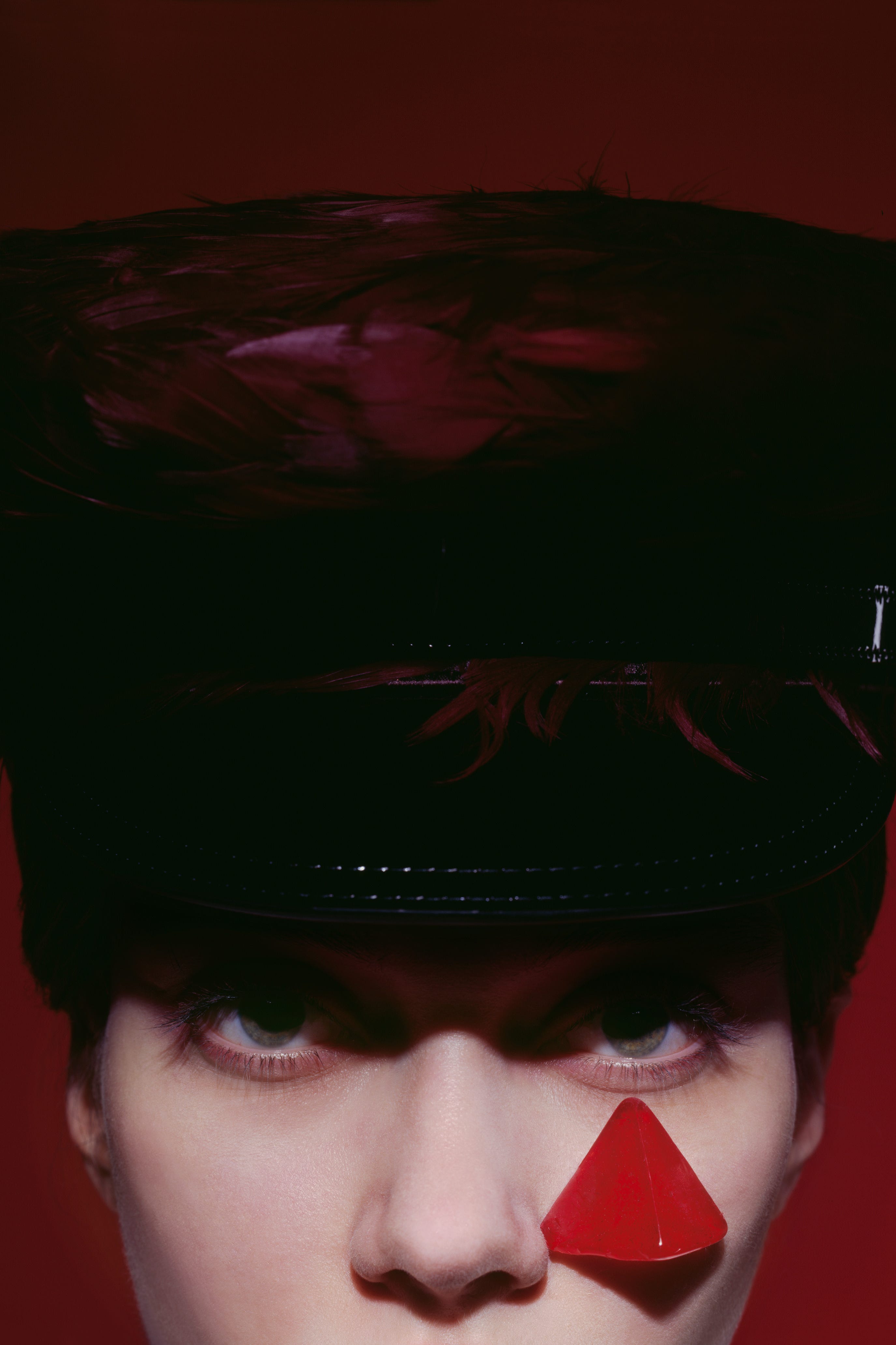 a close up of a woman in a hat with a triangular red shape below her eye