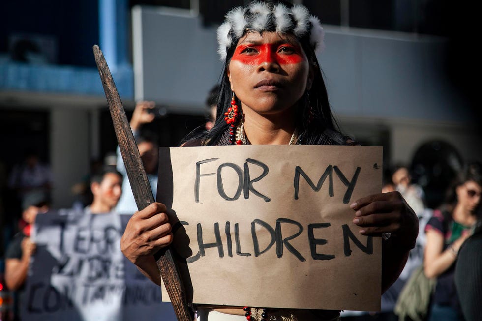 a woman holding a sign that reads "for my children"