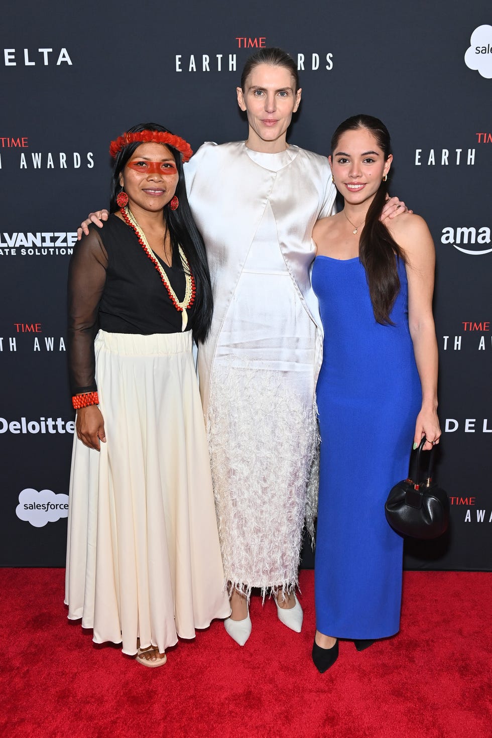 three women posing on a red carpet