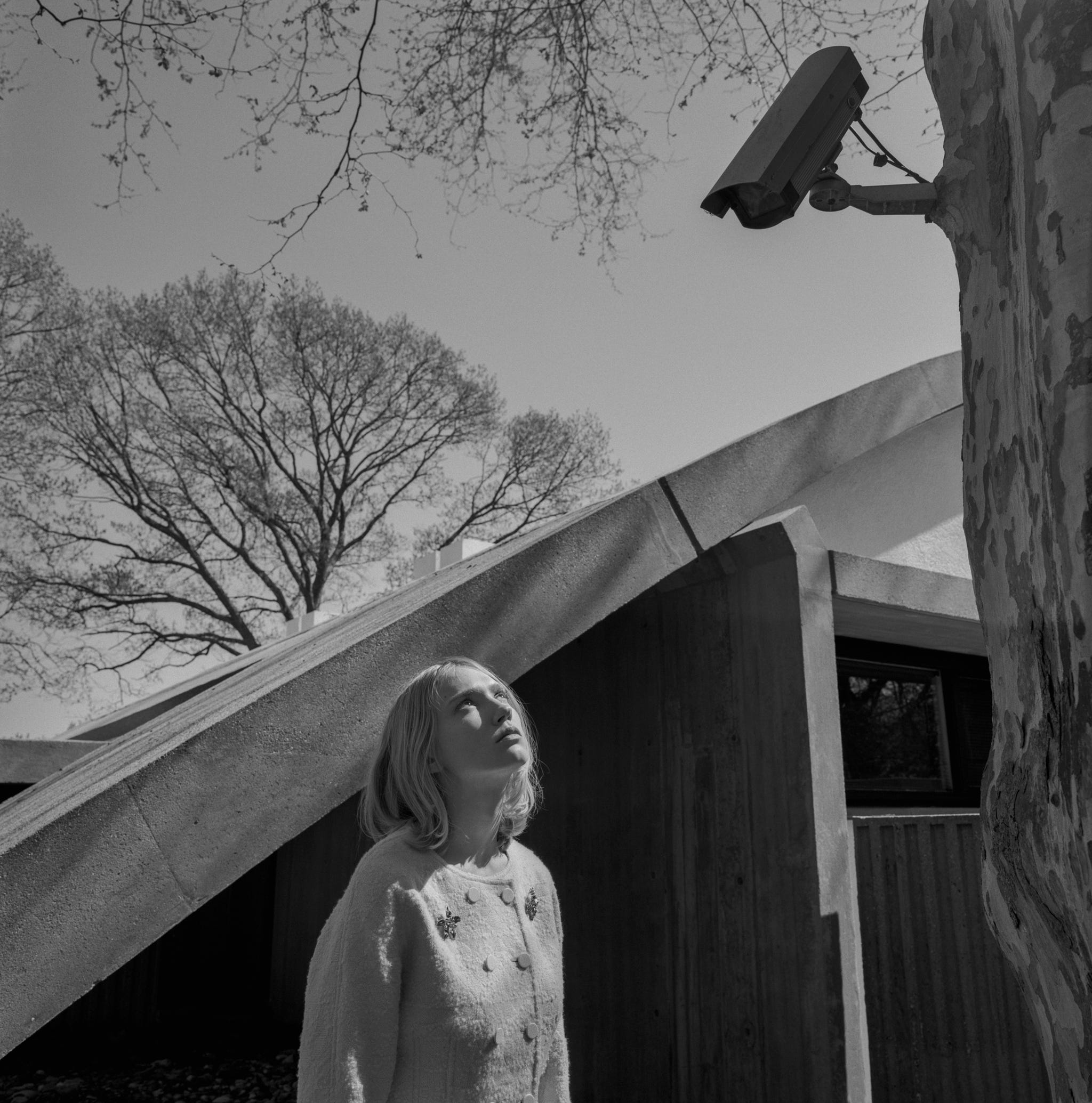 a woman standing in front of a modern building staring up at the sky