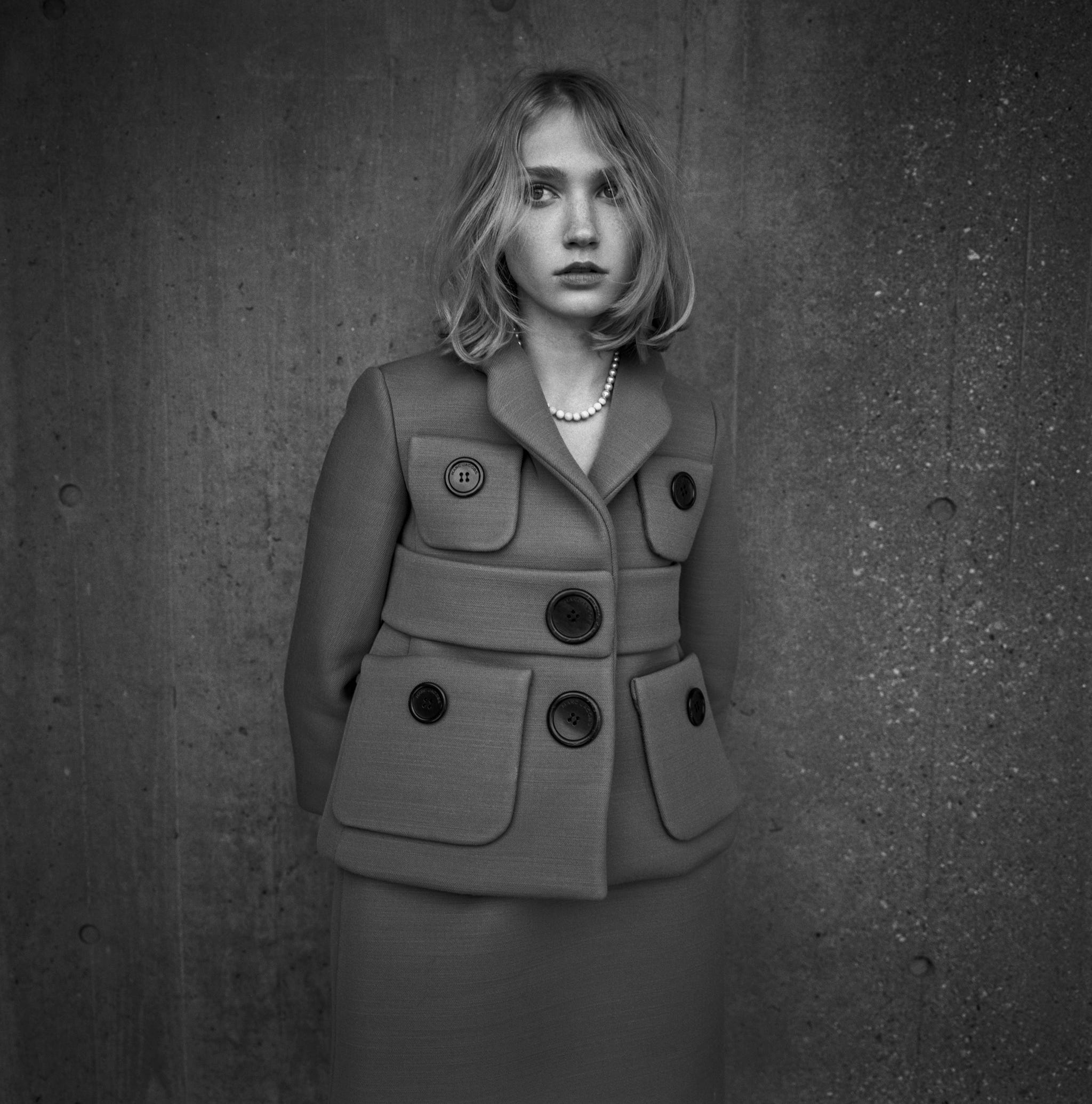 a black and white image of a woman wearing a peacoat and pearls