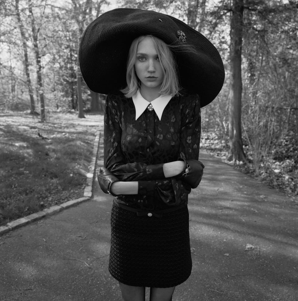 a woman in a black dress and oversized hat