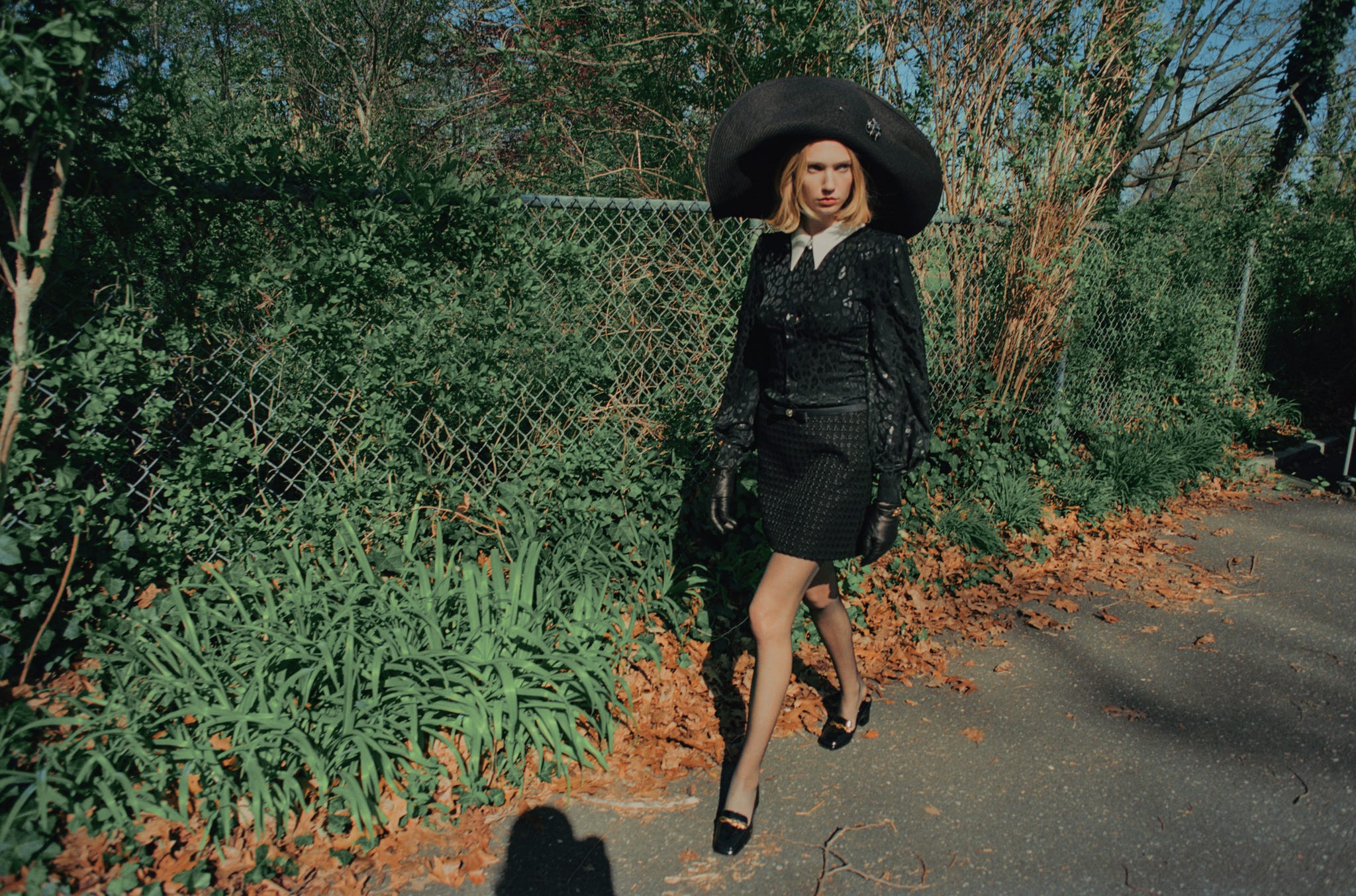 a woman in a black dress and oversized hat