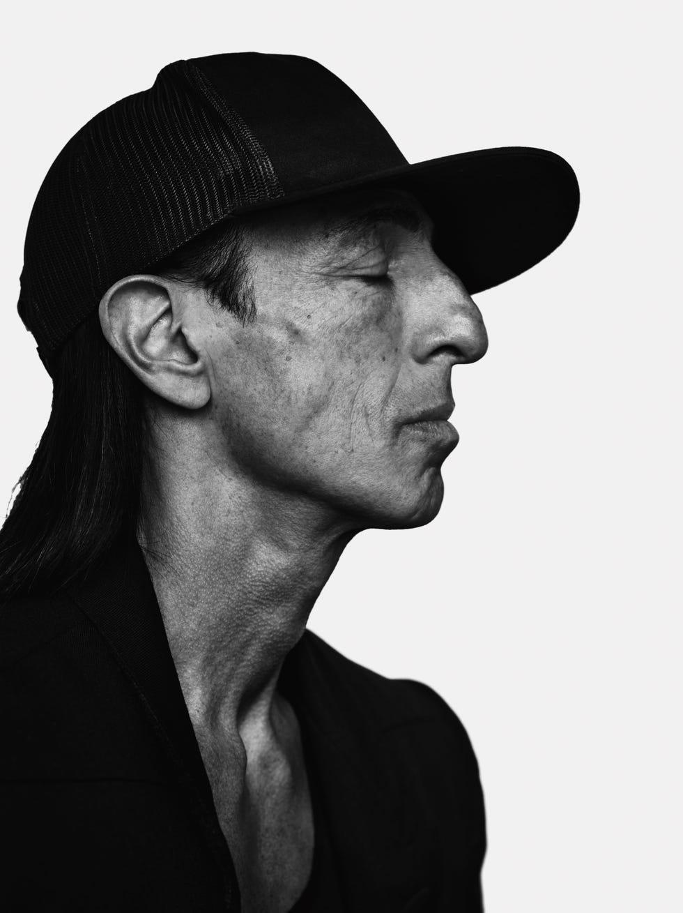 a black and white image of a man in profile wearing a baseball cap