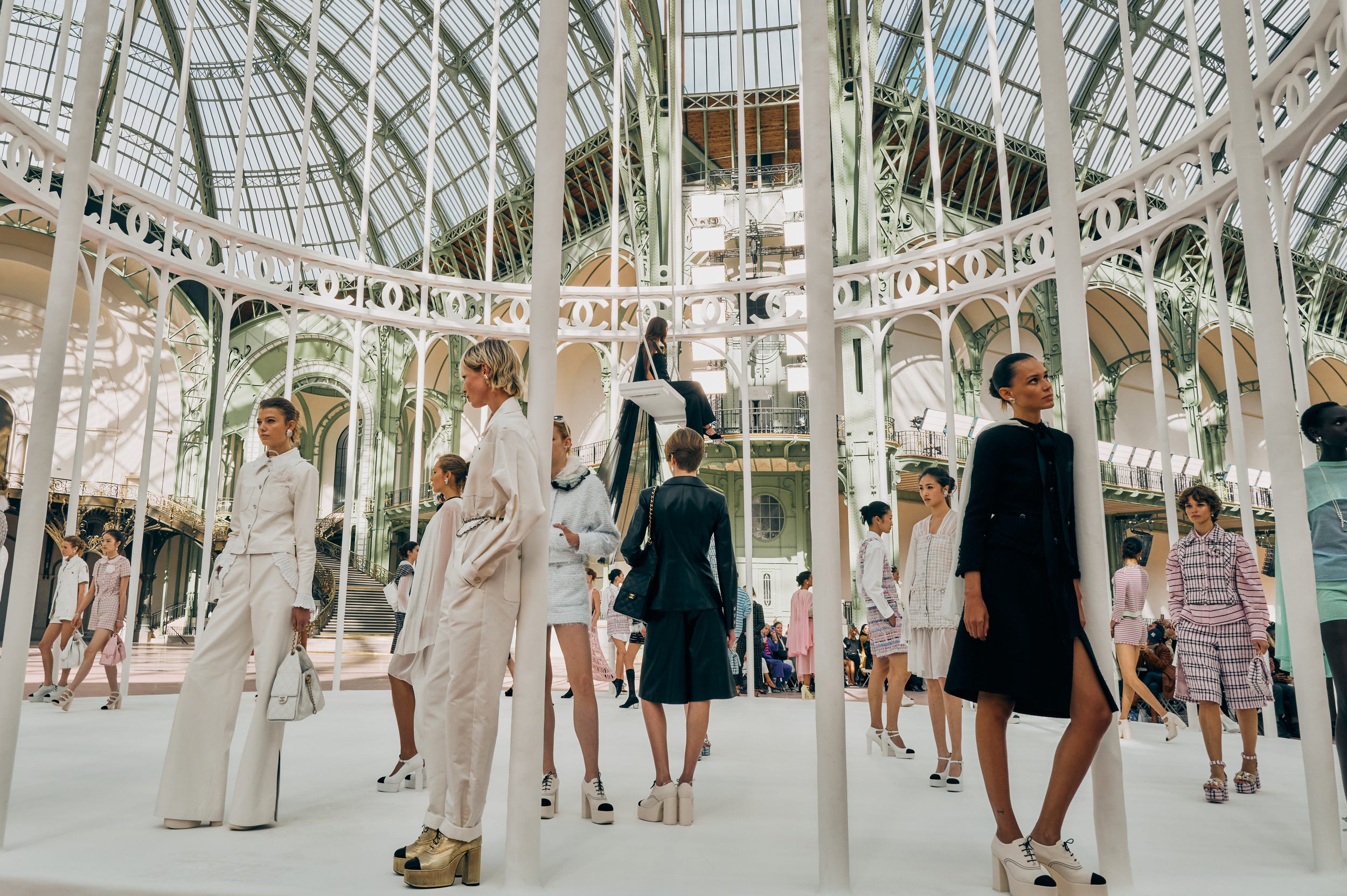 riley keough singing on a swing while a group of models pose beneath her