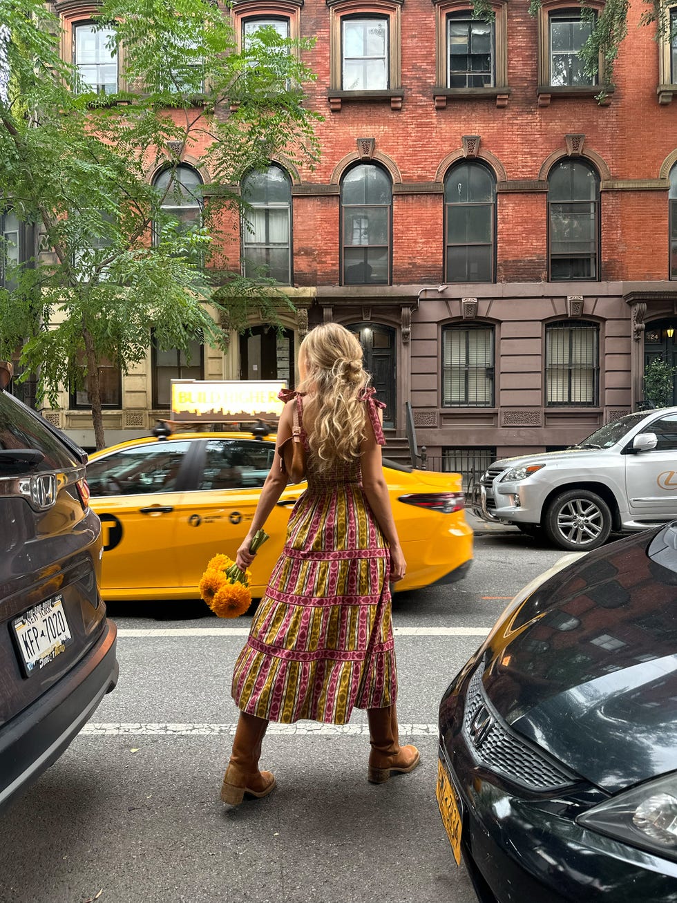 a woman with long, wavy hair is positioned in the foreground, wearing a vibrant, patterned dress with a flared hem