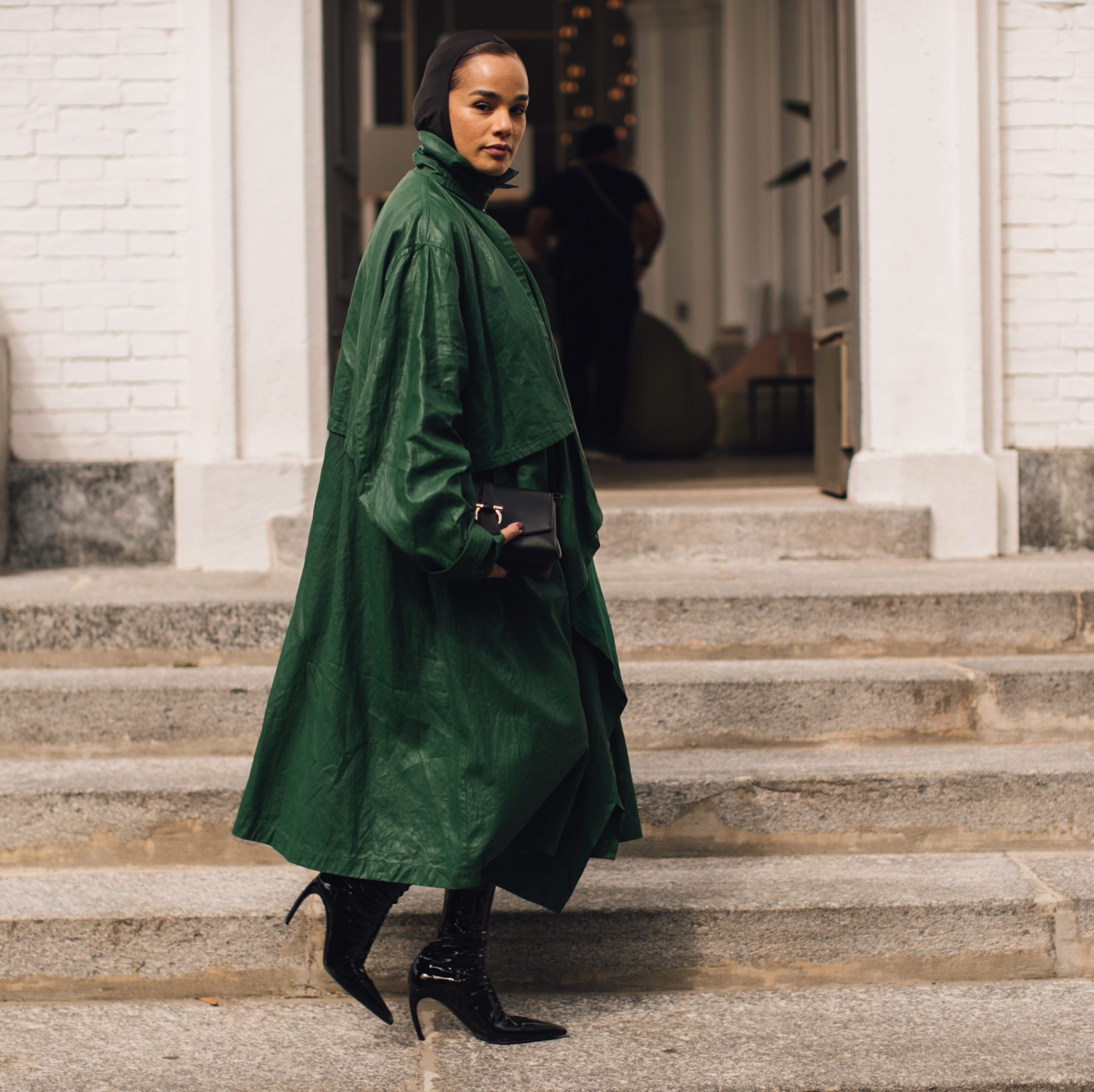 person wearing a green coat and high heels walking down stairs