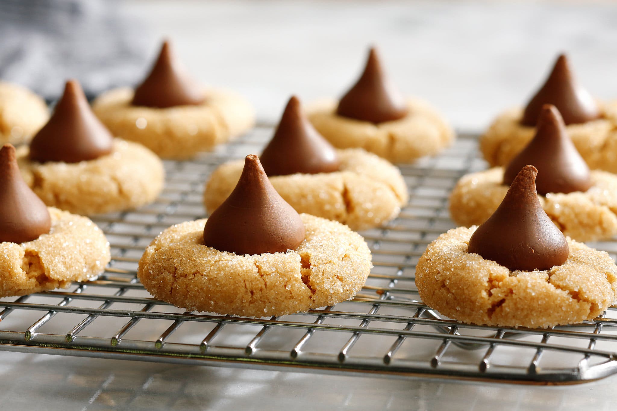 A cooling rack with rows of peanut butter blossoms topped with Hershey Kisses.