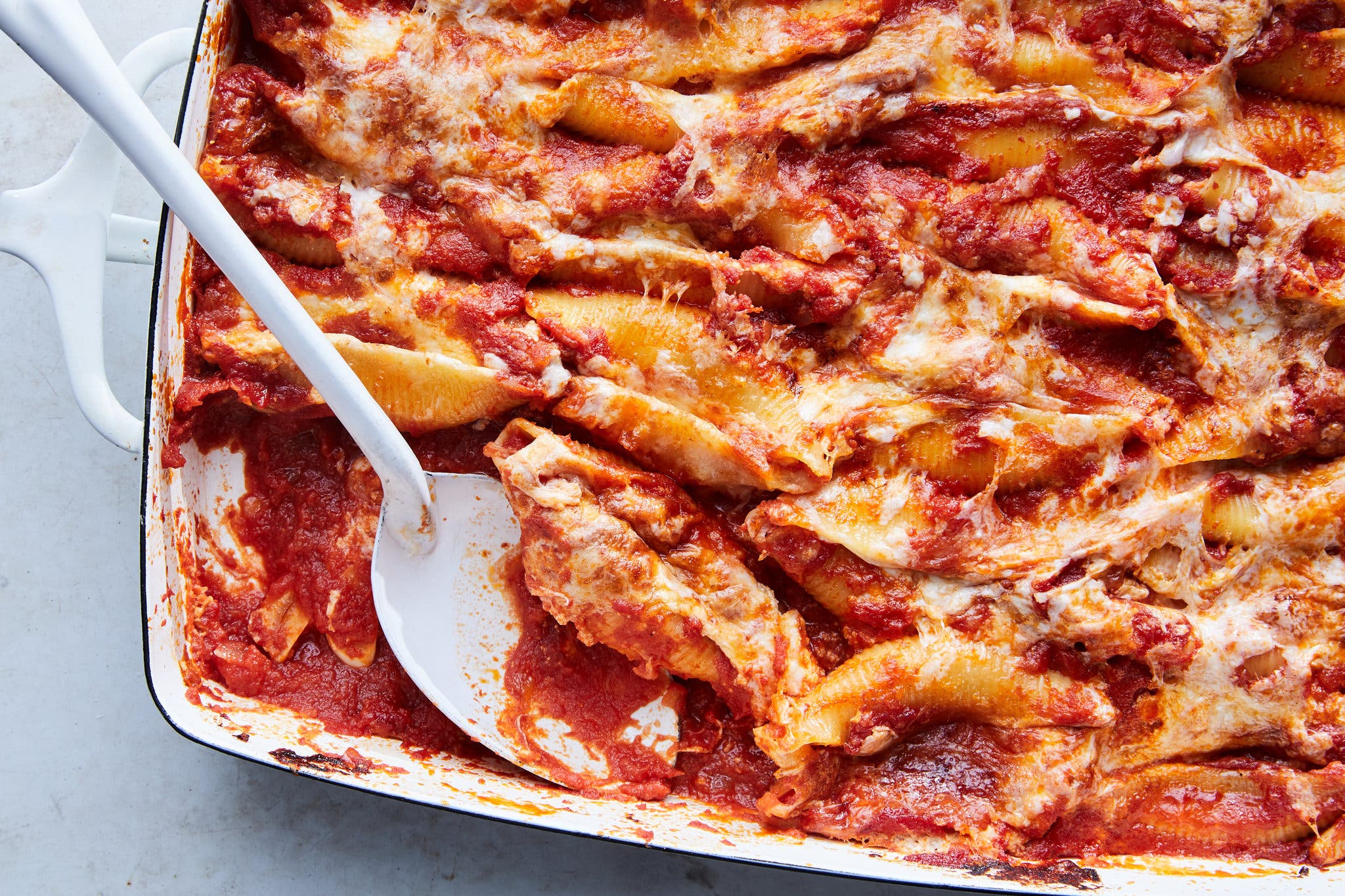 Stuffed pasta shells in red sauce baked into a large casserole dish.