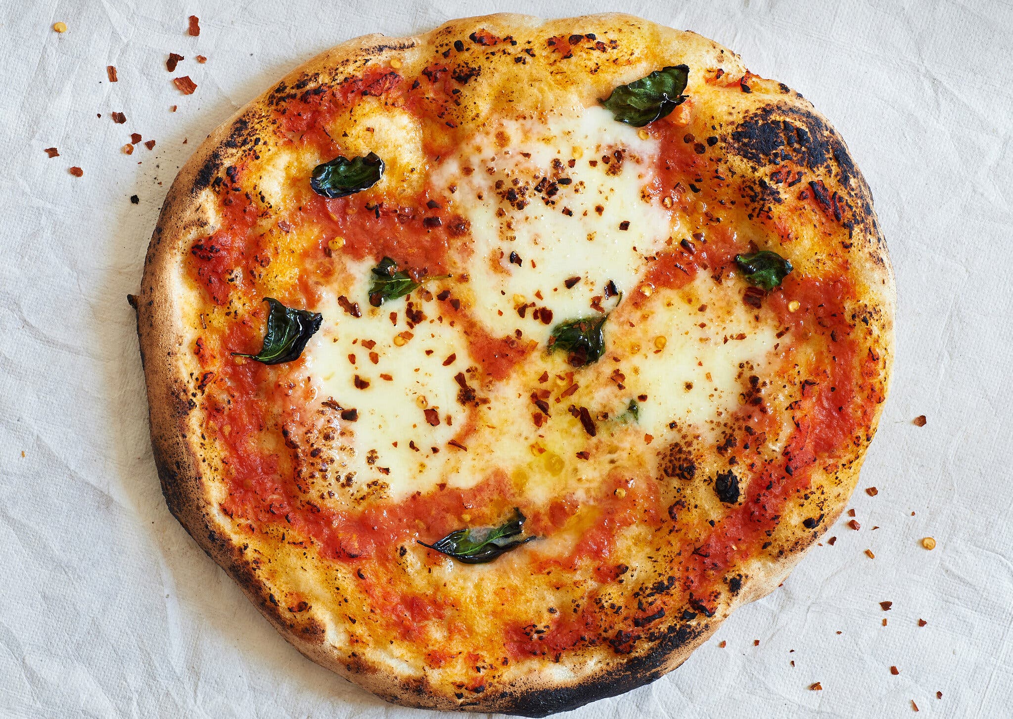 An overhead image of a pizza topped with cheese and herbs.