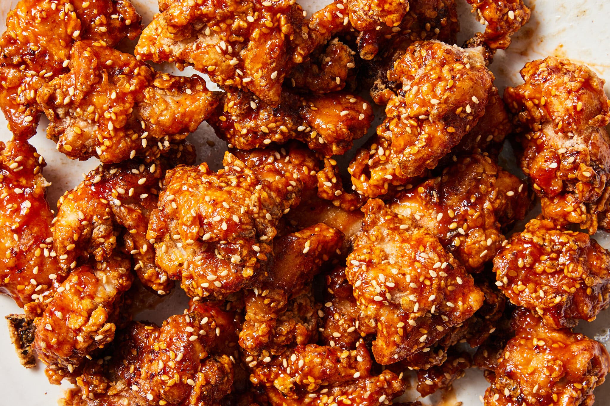 Korean fried chicken is sprinkled with sesame seeds and shown in close-up.