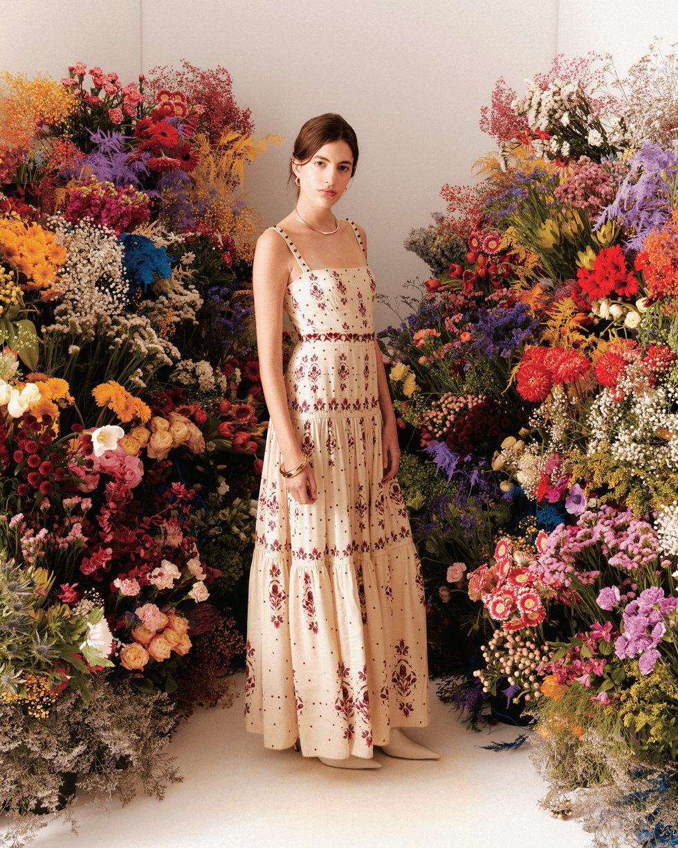 a woman in a floral dress standing in front of a floral arrangement