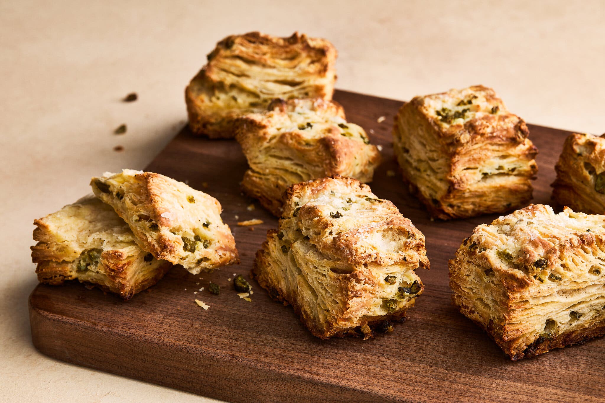 Square biscuits layered with chopped pickles sit on a wooden board.