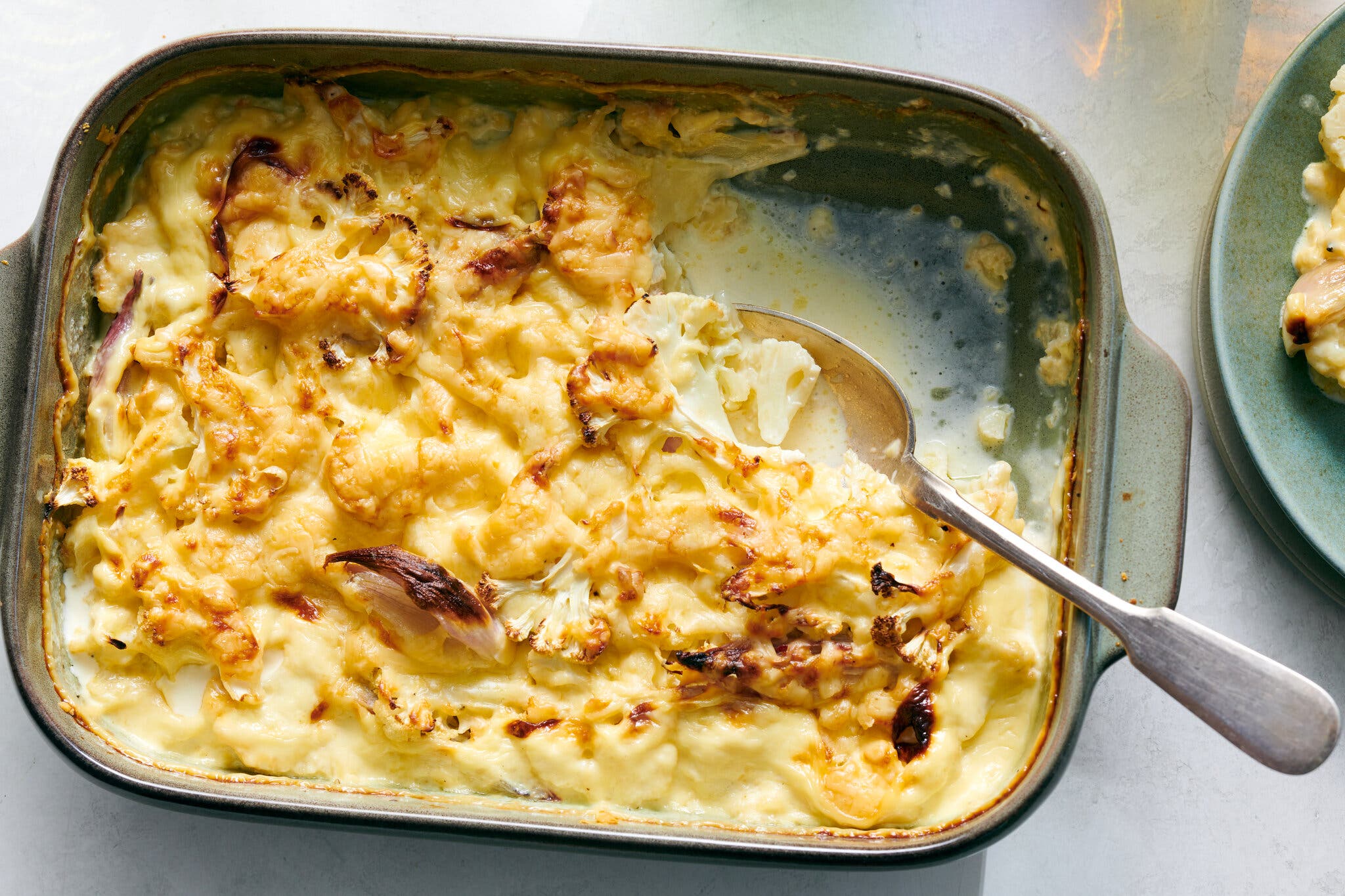 A baking dish is filled with cauliflower and cream sauce and browned on top.