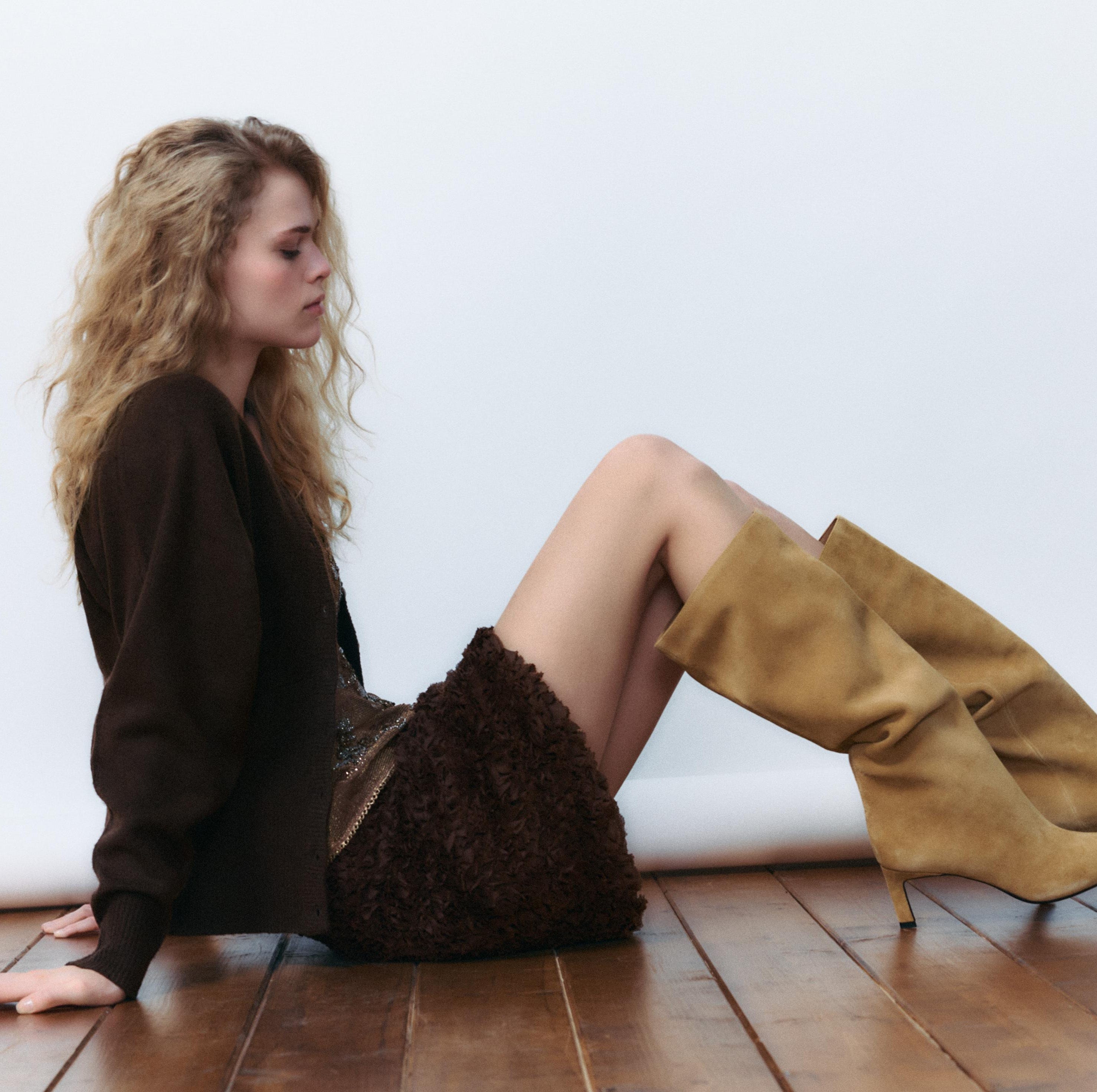 a person sitting on a wooden floor wearing a stylish outfit