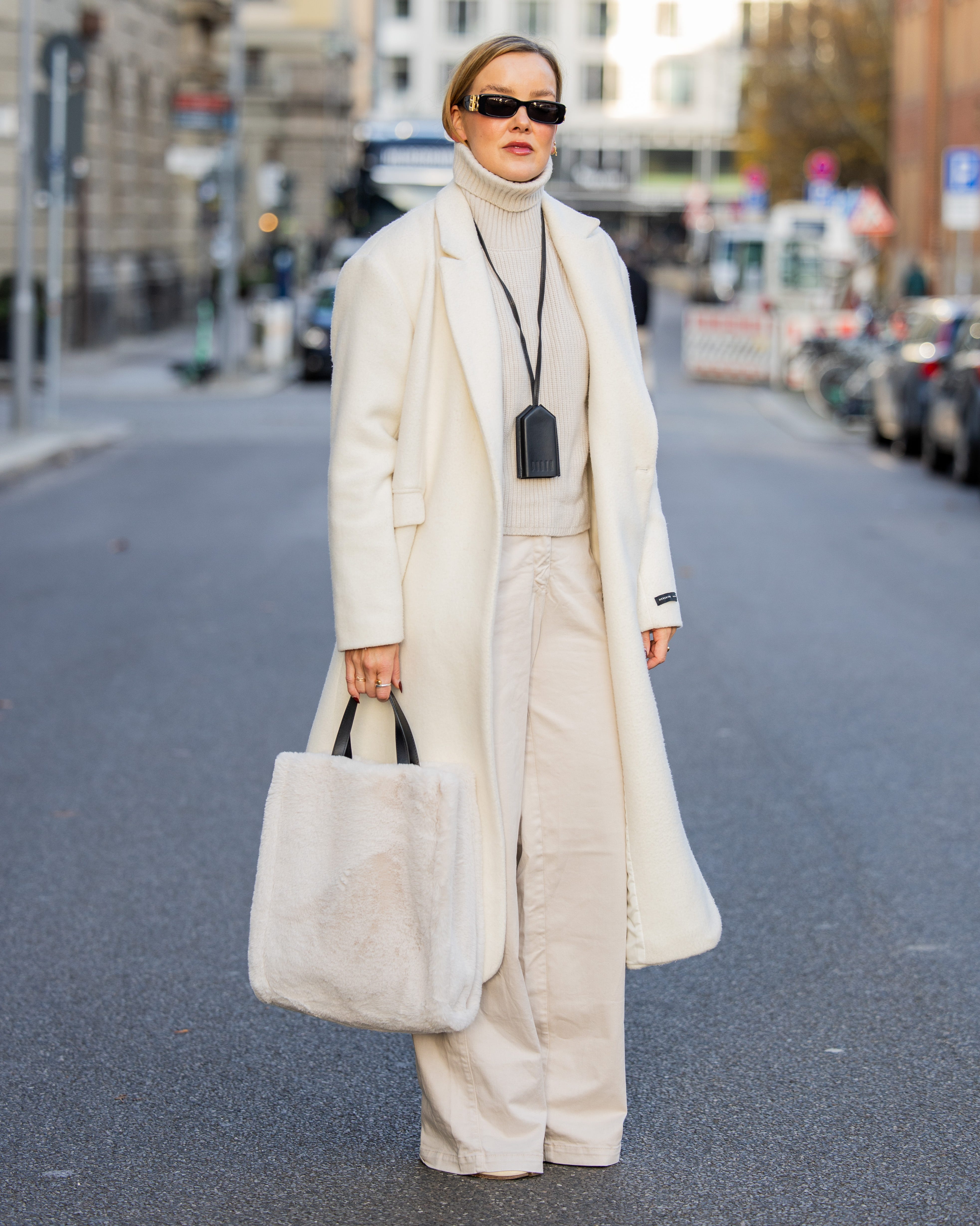 berlin, germany december 03 tina haase wears white maxi coat herskind, white turtleneck sweater, cream wide leg pants beaumont, cream tabi boots maison margiela, cream fauxfur tote bag inwear, black leather keychain necklace podyh, sunglasses balenciaga on december 03, 2024 in berlin, germany photo by christian vieriggetty images