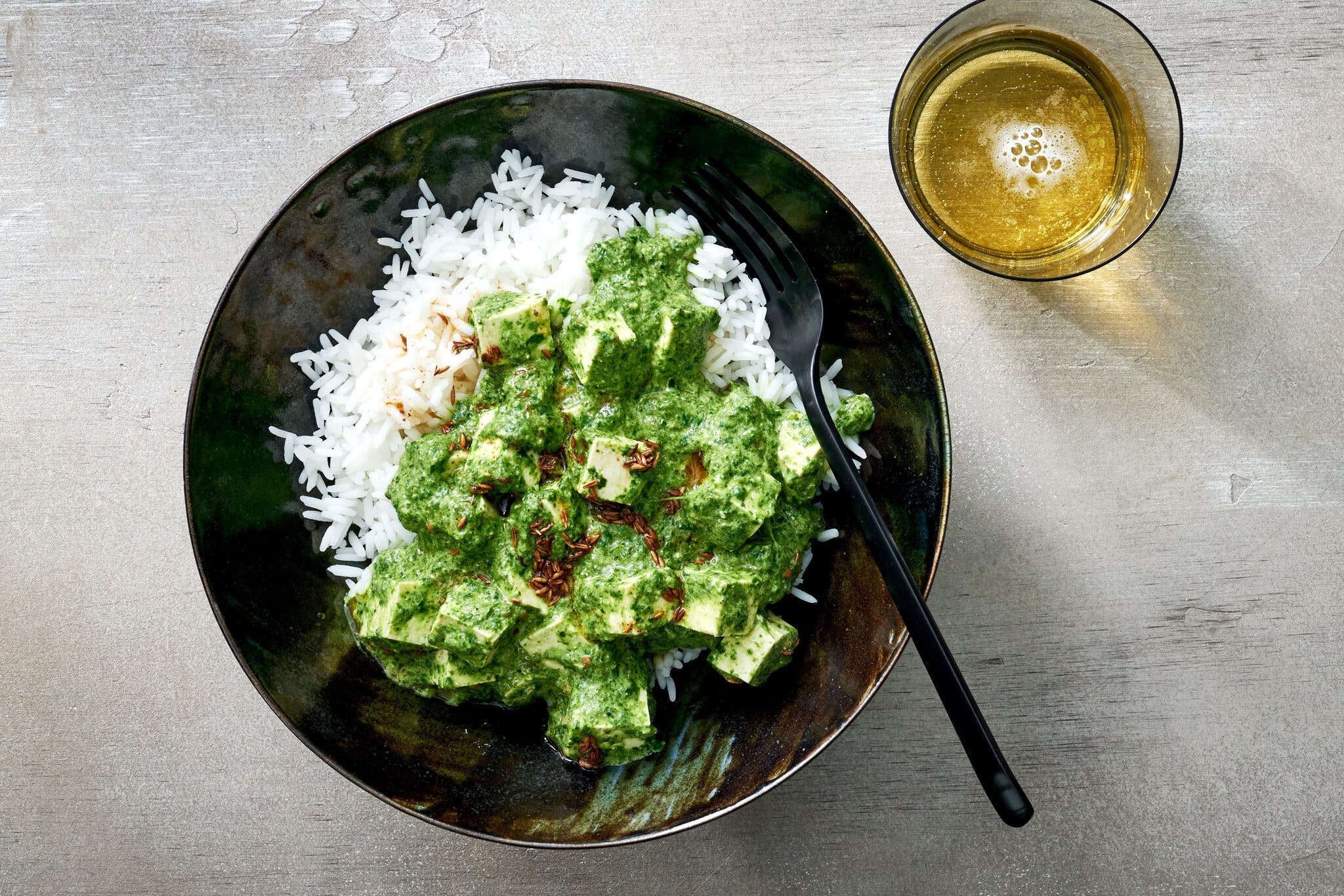 A black bowl filled with coconut saag topped rice.