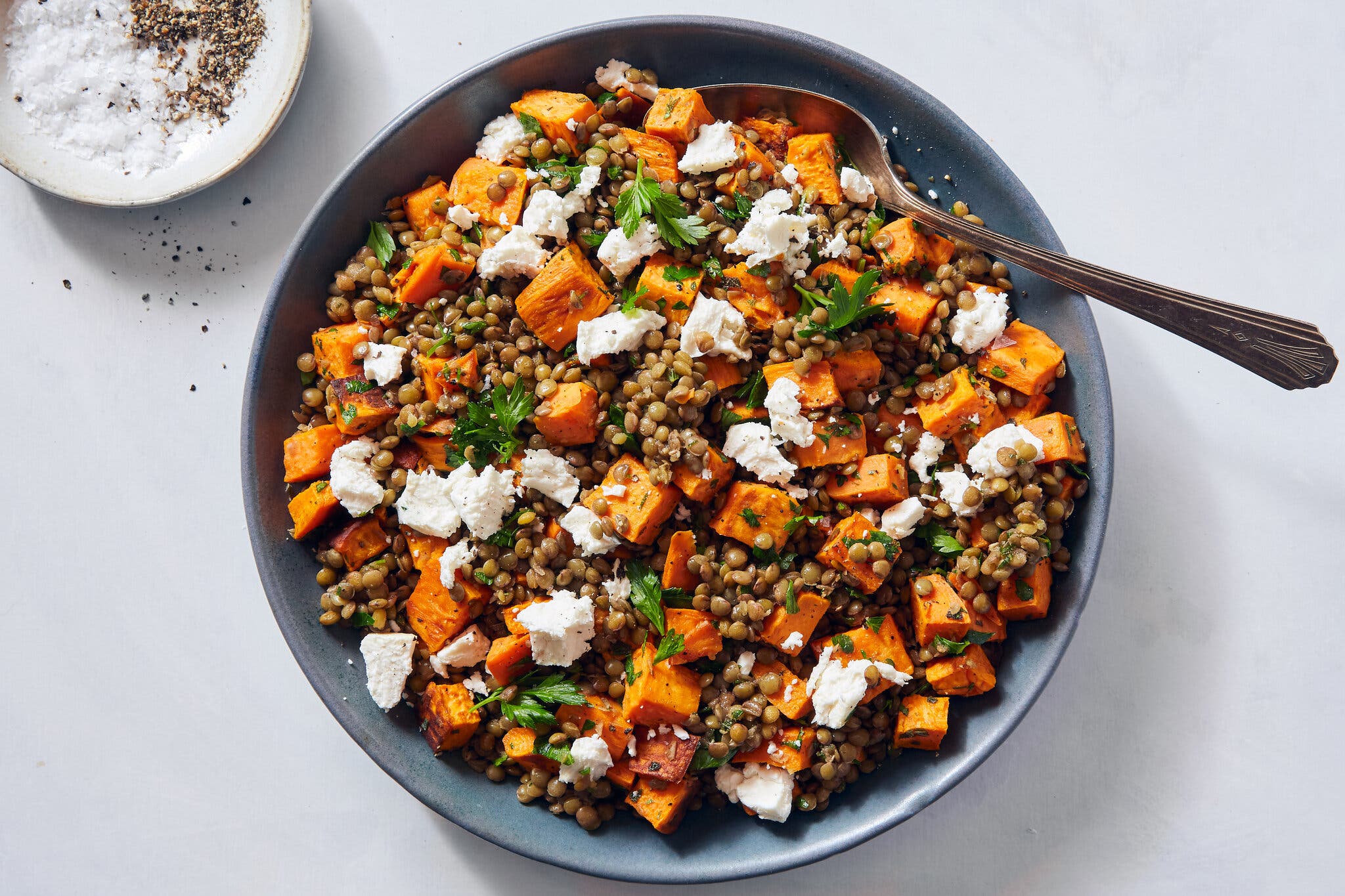 Cubed sweet potato, lentils and feta sit in a blue bowl.